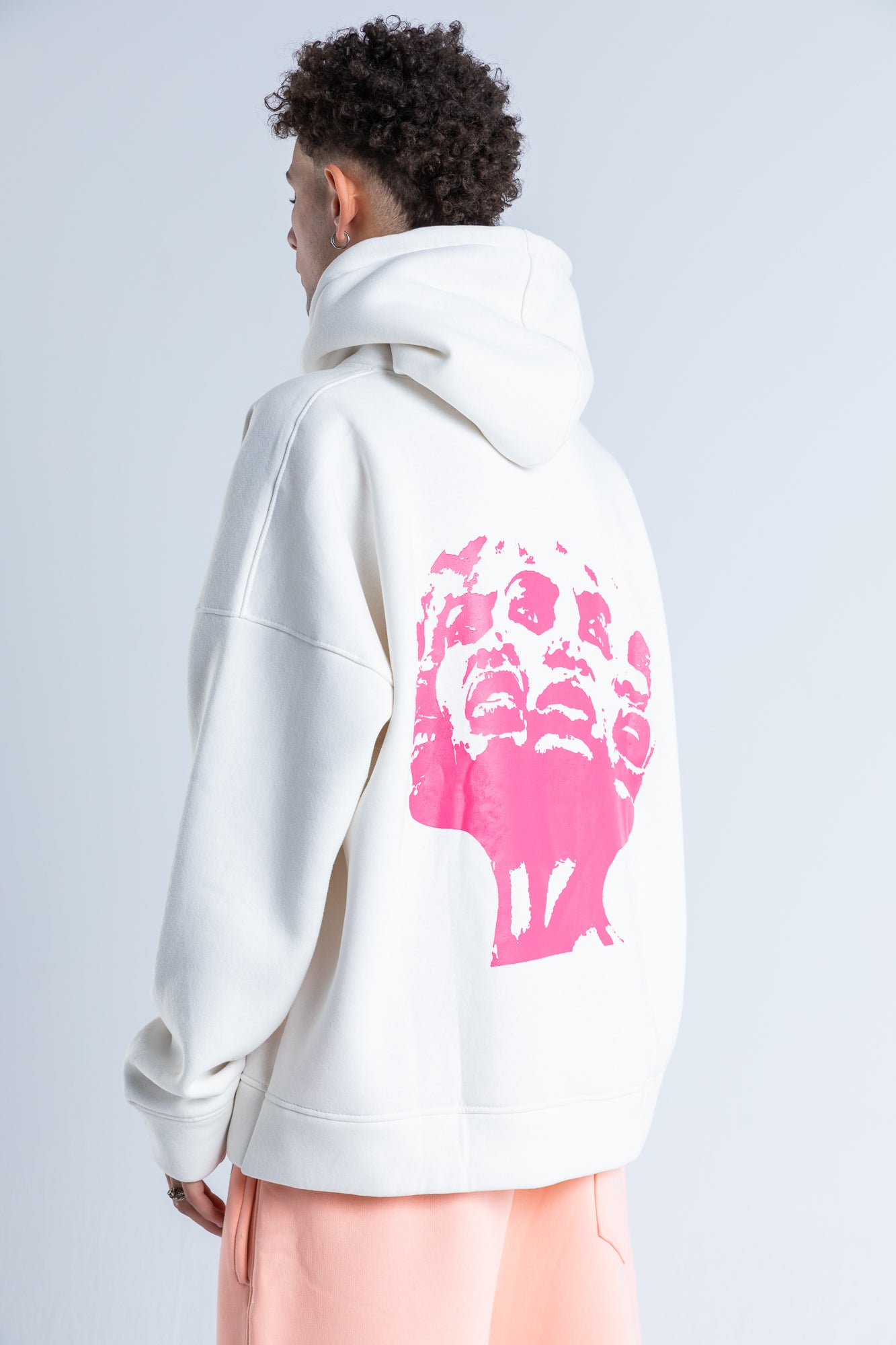 Side view of pink distortion hoodie highlighting the drawstring hood, long sleeves, and cozy silhouette.