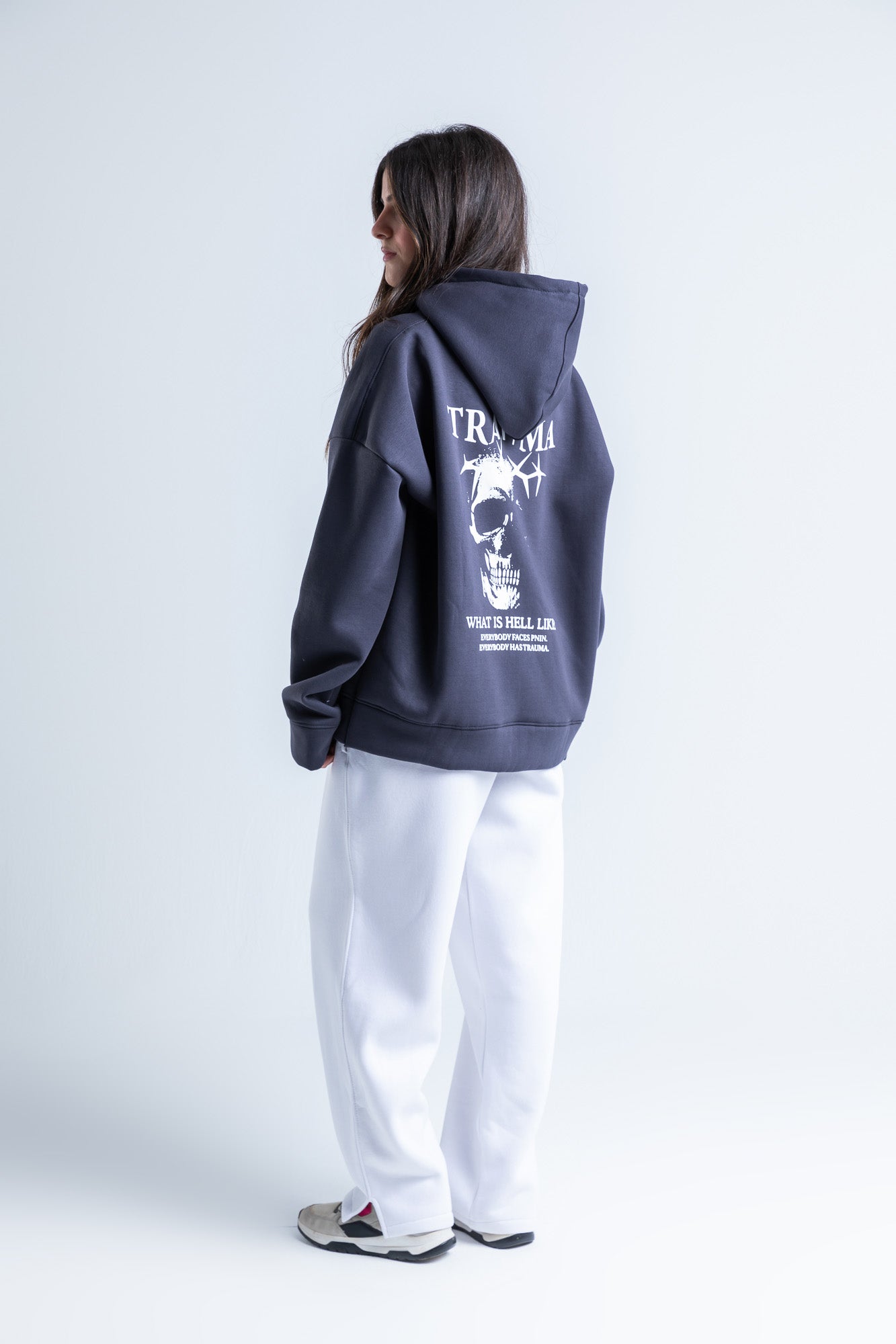 Side view of Trauma hoodie highlighting long sleeves, a drawstring hood, and a laid-back silhouette.
