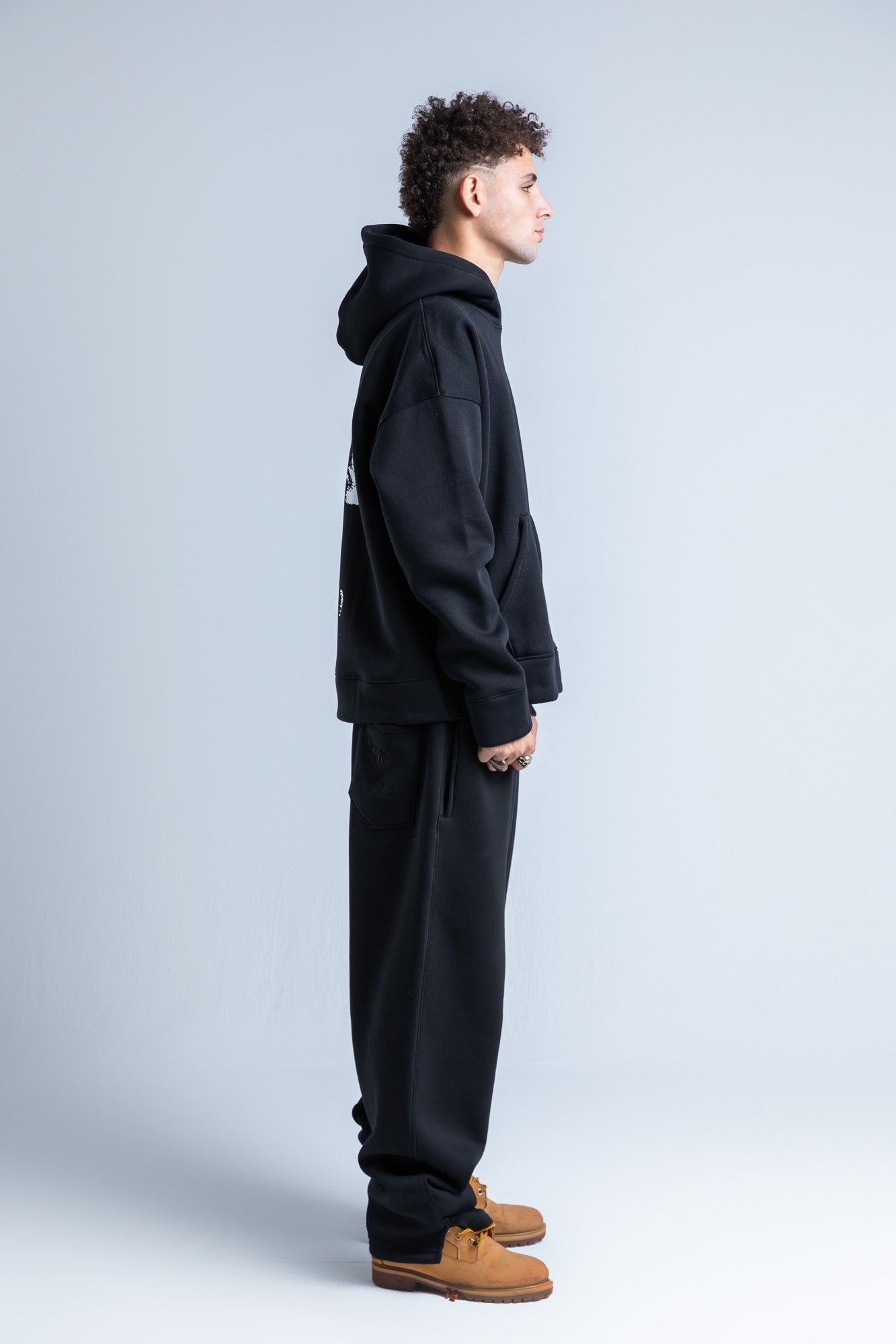 Side view of Puff Pass hoodie highlighting long sleeves, a drawstring hood, and a casual, relaxed silhouette.